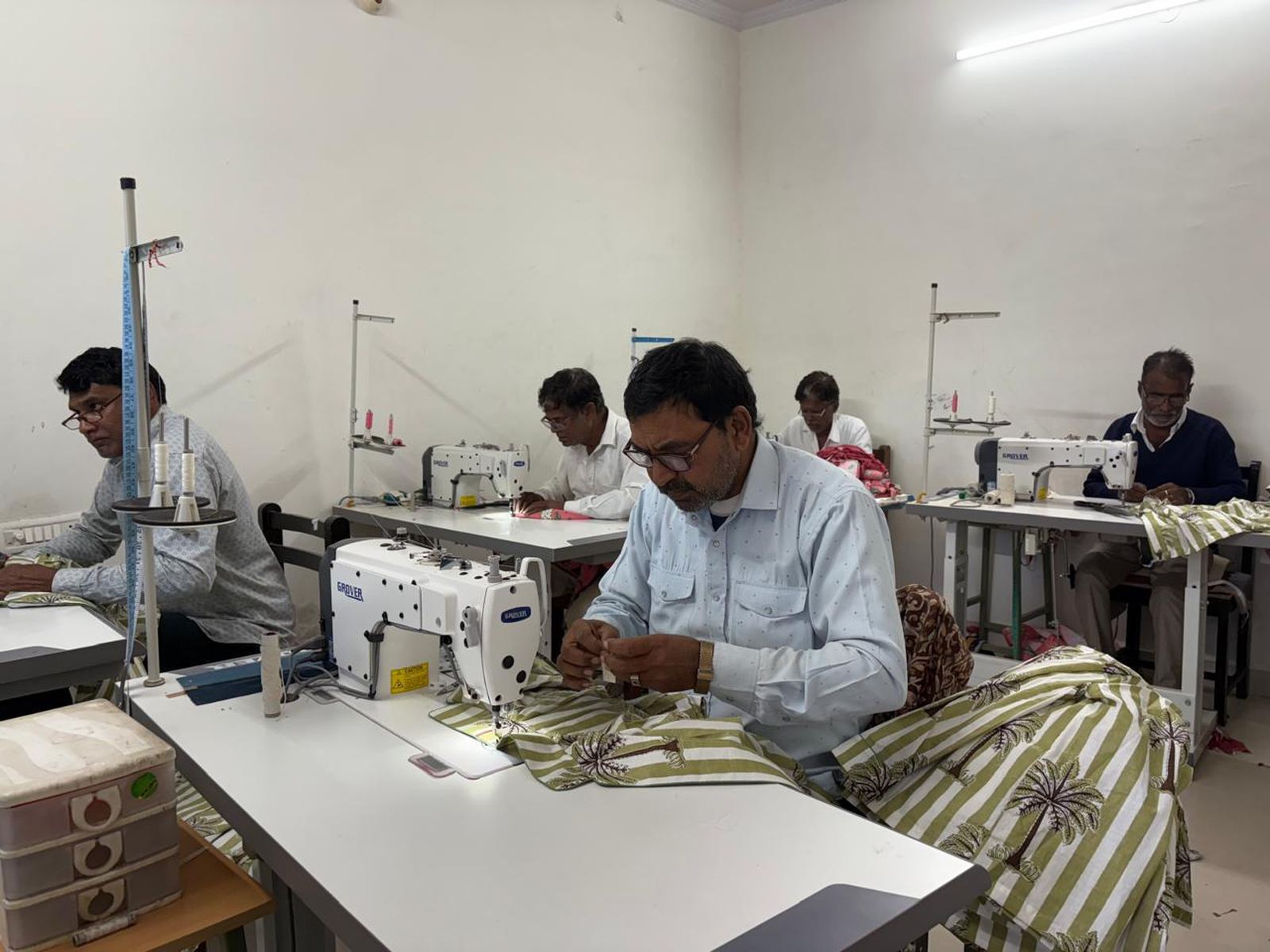 Tailors stitching printed cotton fabric on the Stree Vardhini production floor
